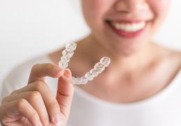 closeup of woman holding Reveal® clear aligner 