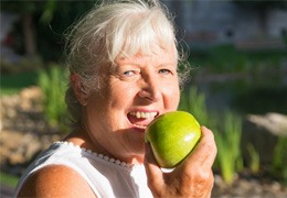 Woman eating apple with dentures in Goodlettsville