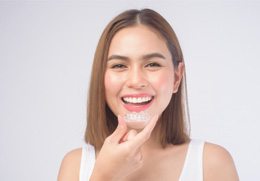 patient smiling while holding Reveal aligner
