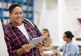 student standing in a library with healthy smile thanks to regular dental checkups