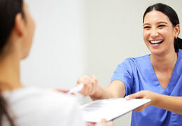 dental assistant smiling while handing patient form