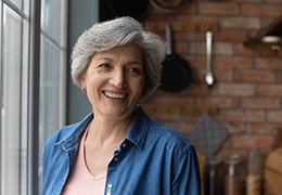 Woman smiling by a window with dentures