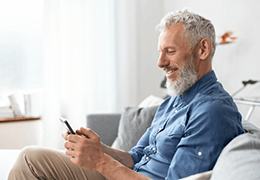 a mature man with dentures smiling while texting