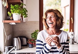 Woman with dentures in Goodlettsville laughing and holding a mug