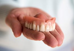 A hand holding a removable upper denture