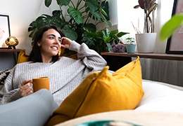 Woman smiling while relaxing on couch with cup of tea