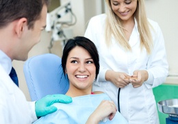 A woman talking with the dentist and dental assistant