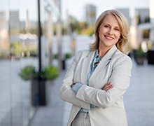 businesswoman standing on a city sidewalk with her arms crossed