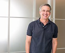 older man in an office standing with his hands in his pockets