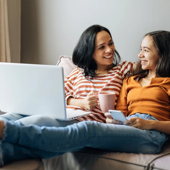 a mom and her teenage daughter sitting on the couch together