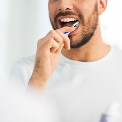Man brushing his teeth in front of mirror