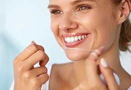 young woman smiling while holding dental floss
