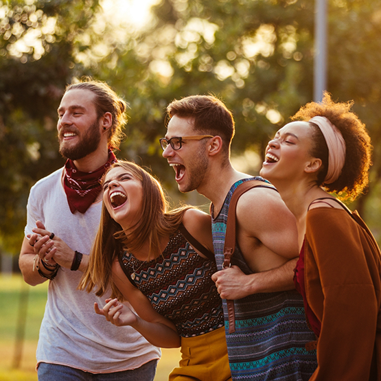 Four adults laughing outside together