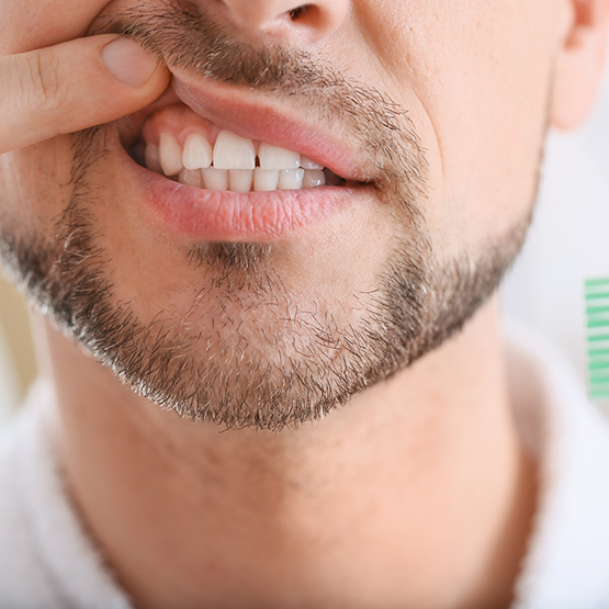 Close up of a person pointing to their gums