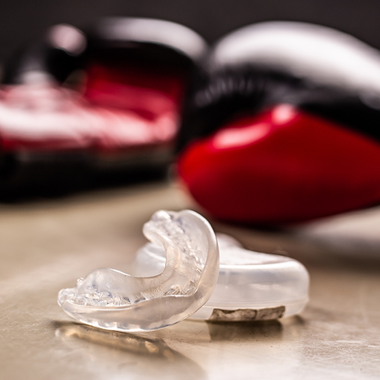 Clear mouthguard on the floor next to two red boxing gloves