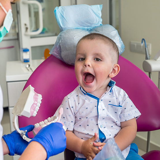 Toddler in the dental chair opening their mouth wide