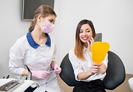 Dental patient holding mirror and smiling