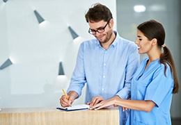 Patient filling out form at dental office front desk