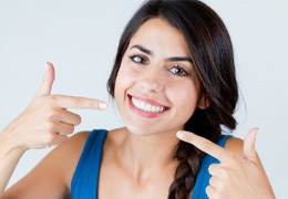 young woman pointing to her smile