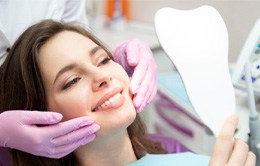 patient smiling while looking into dental mirror