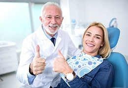Patient and dentist smiling and giving thumbs up