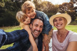 family of four smiling in forest