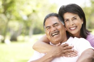 Smiling couple with dental implants in Goodlettsville outside in summer