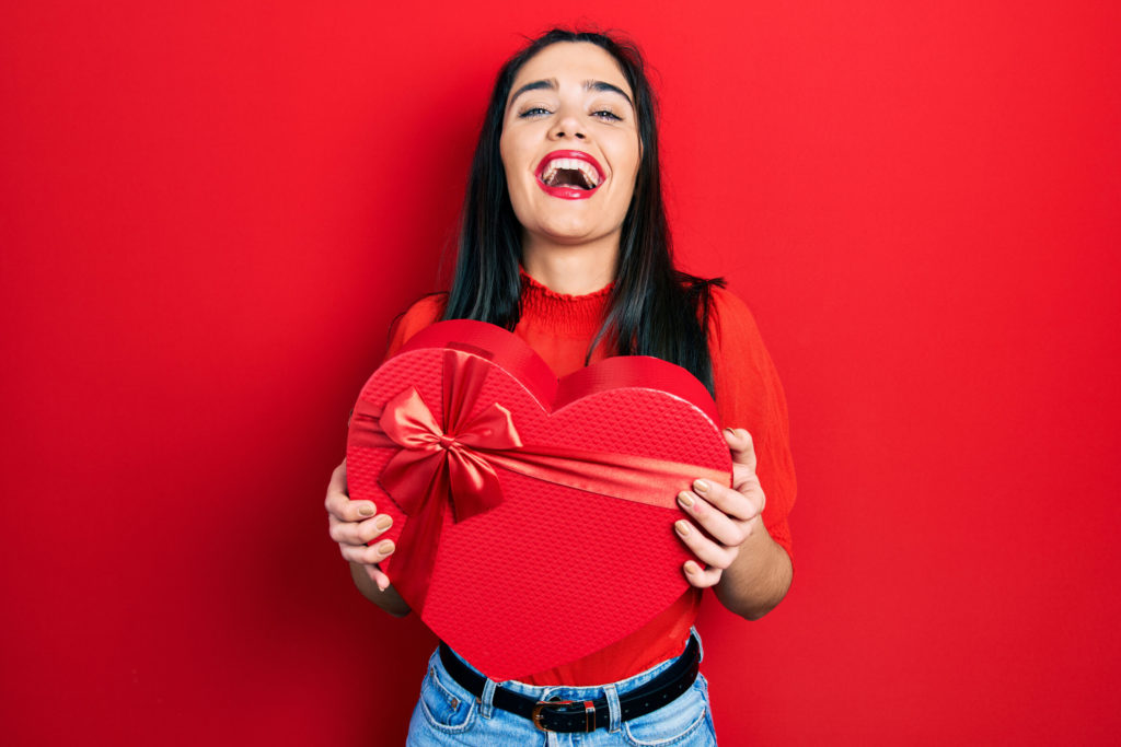 smiling person holding box of Valentine’s Day candy