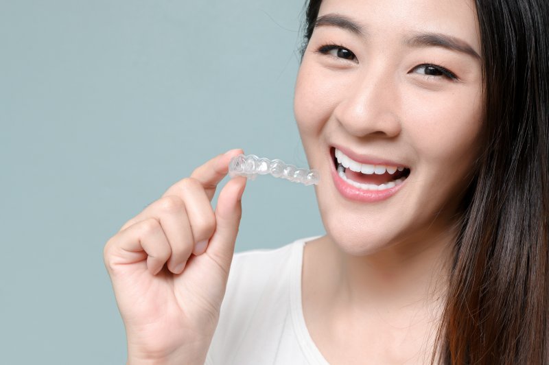 smiling woman holding clear aligners