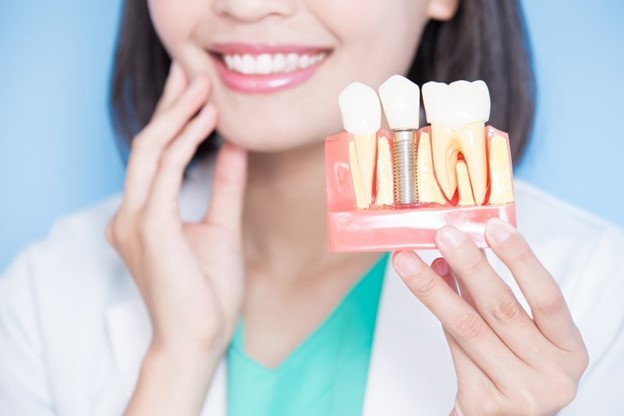 dentist holding out a model of a dental implant