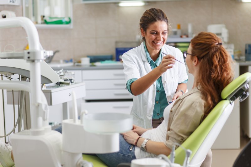 Smiling dentist examines woman.