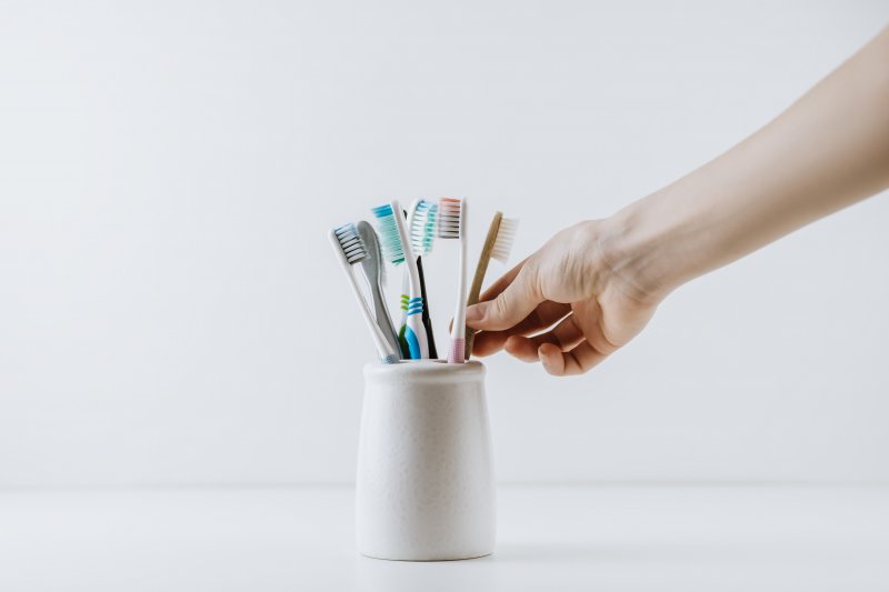 Hand reaches for toothbrushes in holder