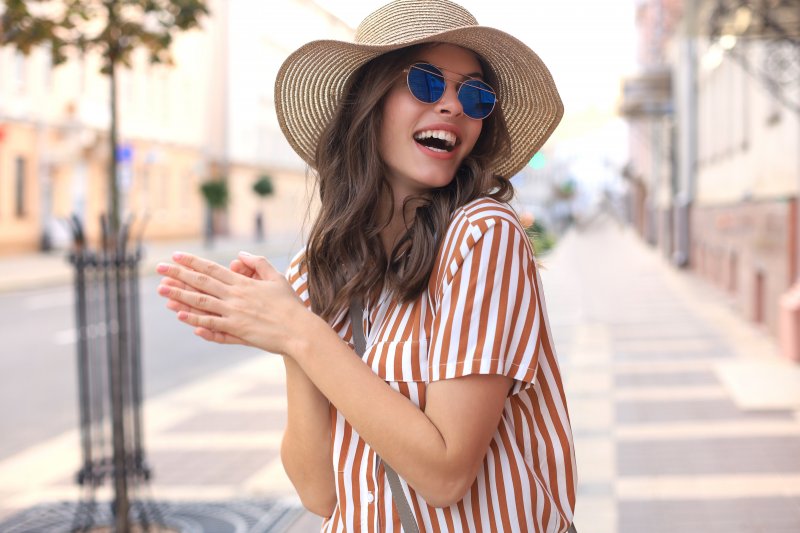 woman wearing big hat and smiling while outside