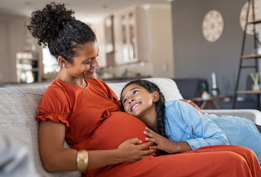 Pregnant mom with older child hugging belly