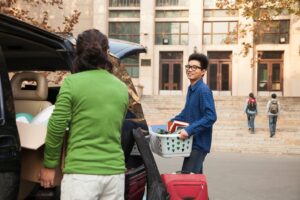 College kid carrying basket moving into dorm.