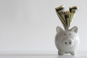 Cash stuffed into top of piggy bank.